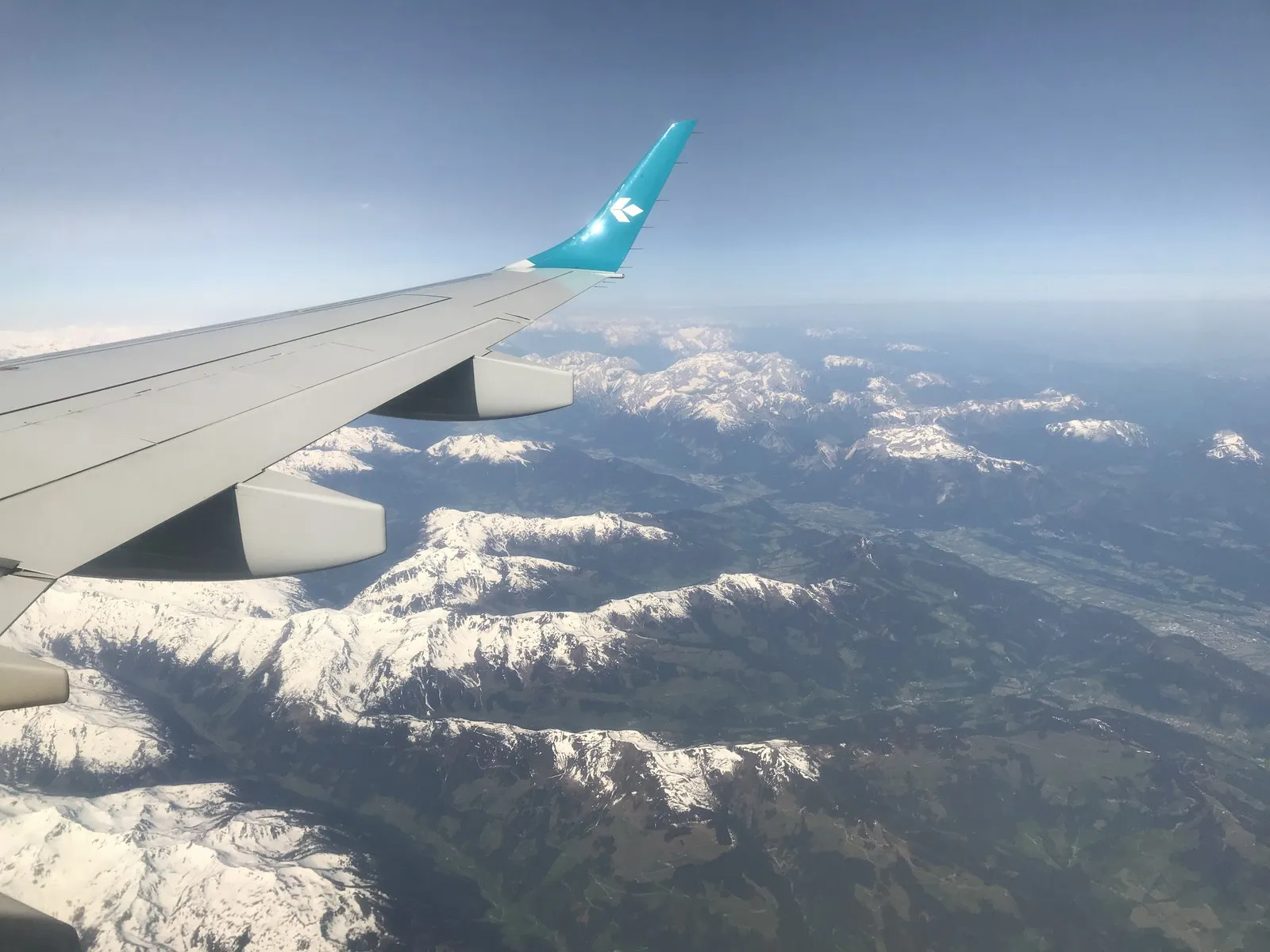 飛行機の翼越しに見える雪をかぶったアルプスの山々
