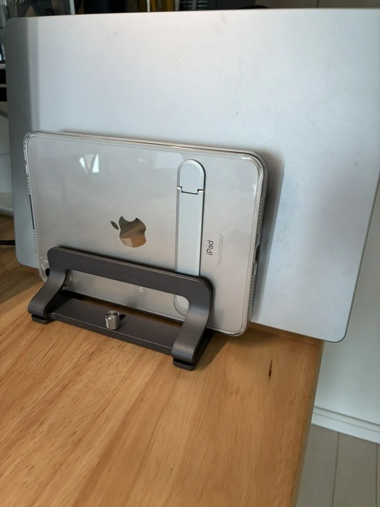 UGREENの縦置きスタンドにMacBookとiPad miniを並べて立てた状態。手前中央に手回しネジが見える