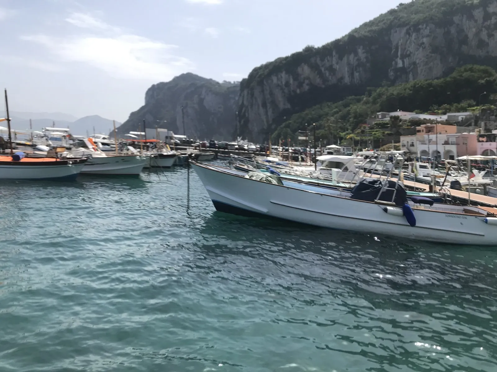 カプリ島の港。停泊する小舟の奥に切り立った山と街並みが見える